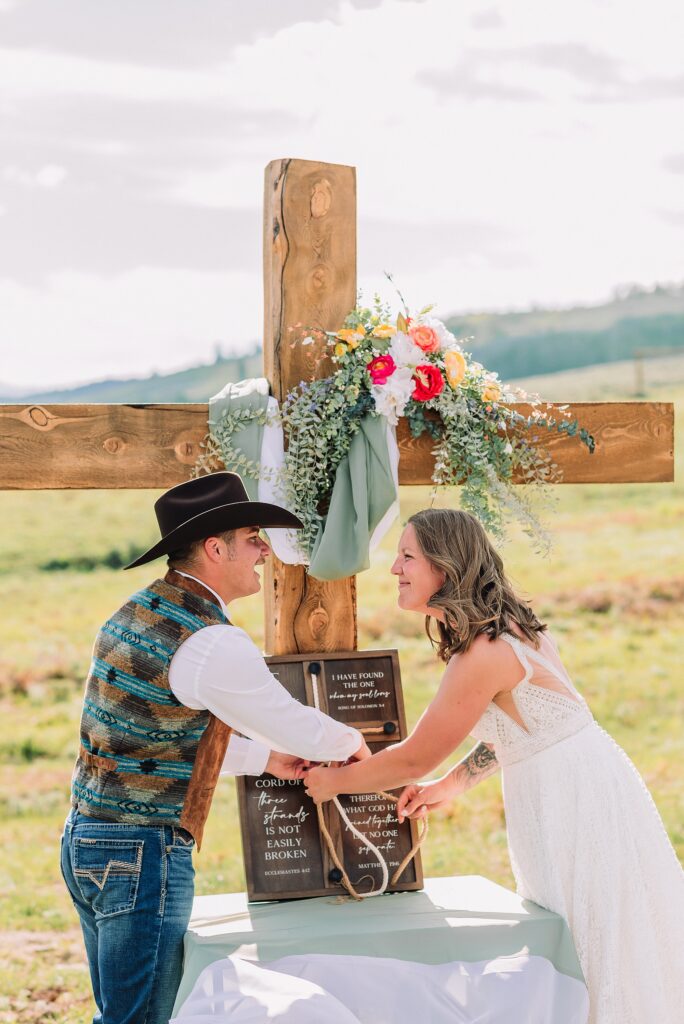 Rustic Wyoming outdoor wedding reception dance floor Faith-based knot tying wedding ceremony Wyoming Candid hilarious cake cutting wedding photos Two-day Wyoming wedding ceremony and reception photography destination Wyoming wedding photography
