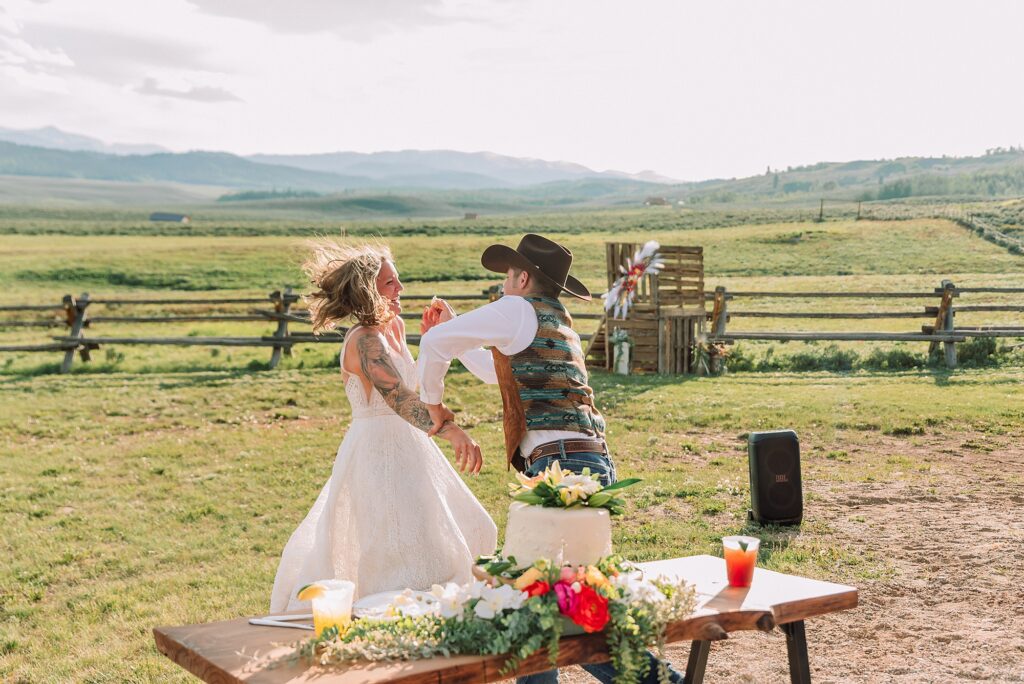 Rustic Wyoming outdoor wedding reception dance floor Faith-based knot tying wedding ceremony Wyoming Candid hilarious cake cutting wedding photos Two-day Wyoming wedding ceremony and reception photography destination Wyoming wedding photography