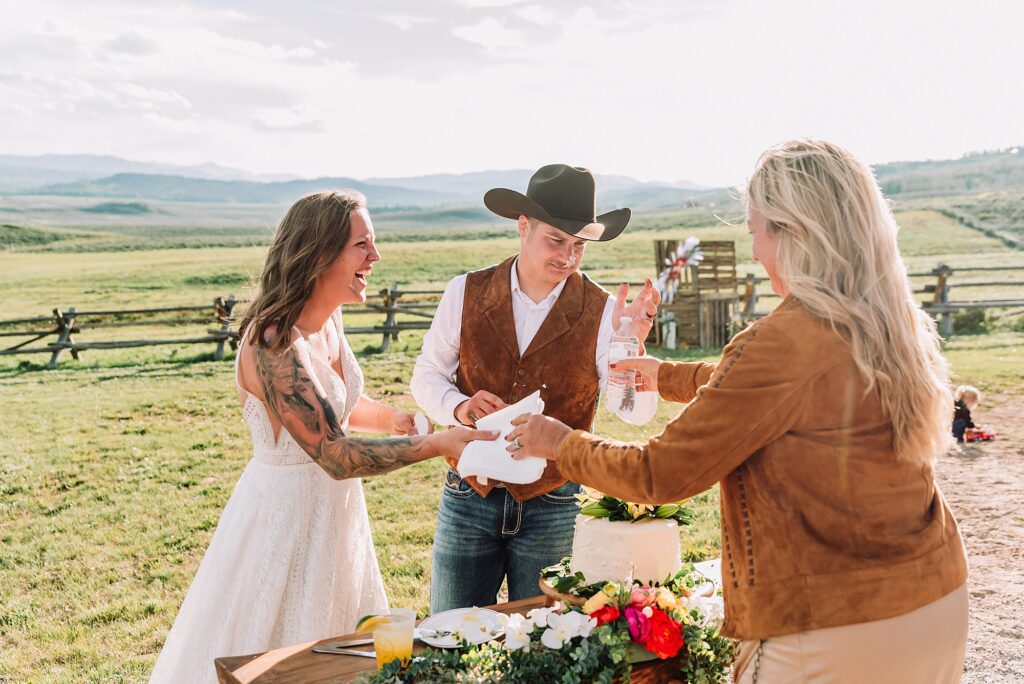 Rustic Wyoming outdoor wedding reception dance floor Faith-based knot tying wedding ceremony Wyoming Candid hilarious cake cutting wedding photos Two-day Wyoming wedding ceremony and reception photography destination Wyoming wedding photography